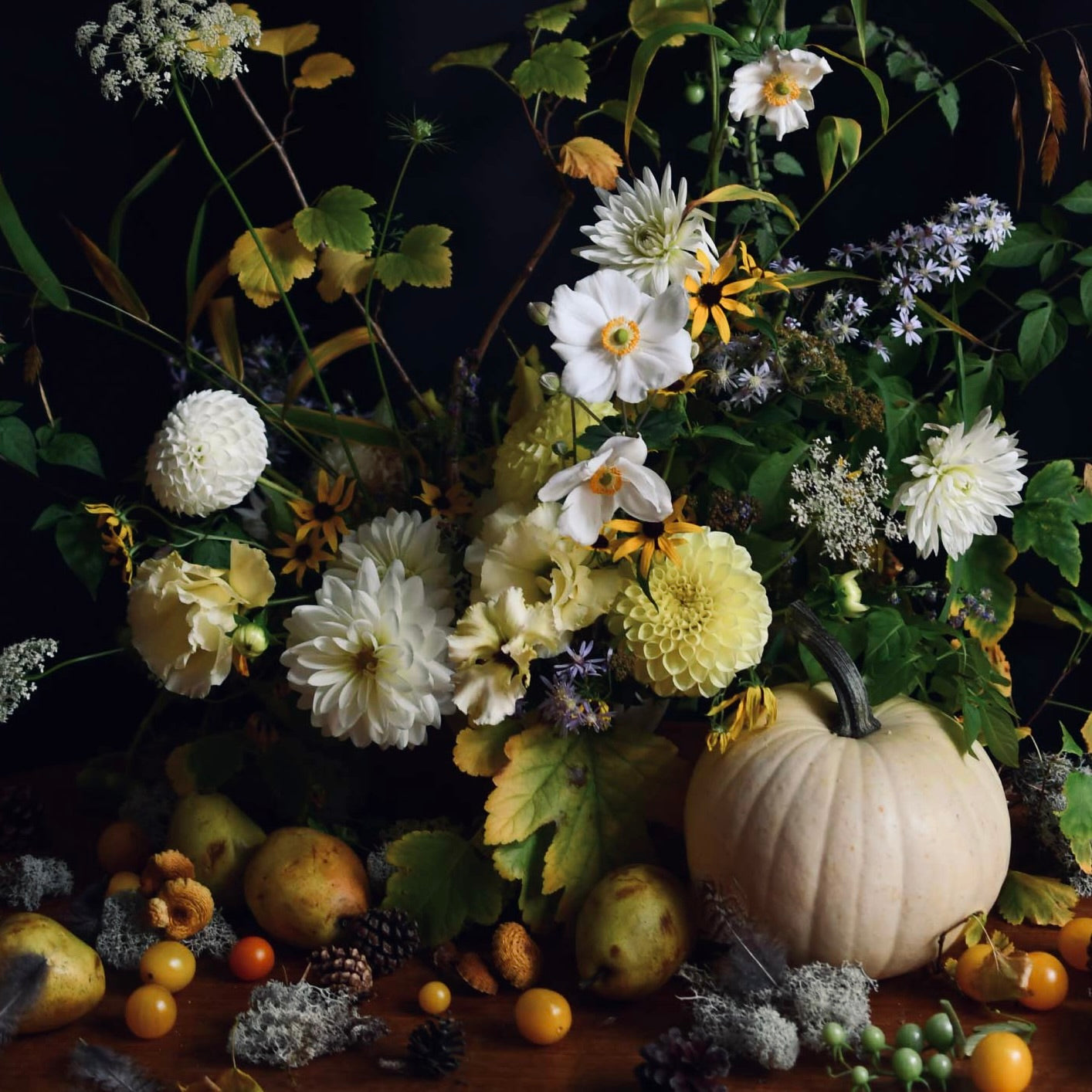 Autumnal still life with pumpkins, fruits, and flowers on a dark background